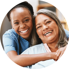 Smiling caregiver hugging happy elderly woman