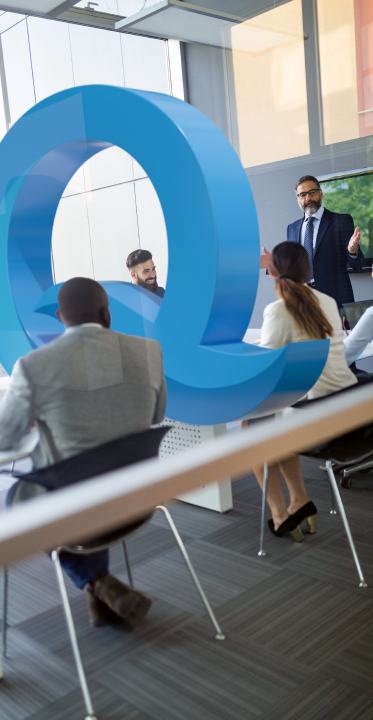 Business meeting with large 3D letter Q.