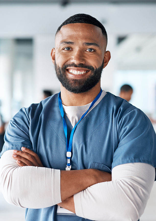 Smiling healthcare professional in scrubs with badge.