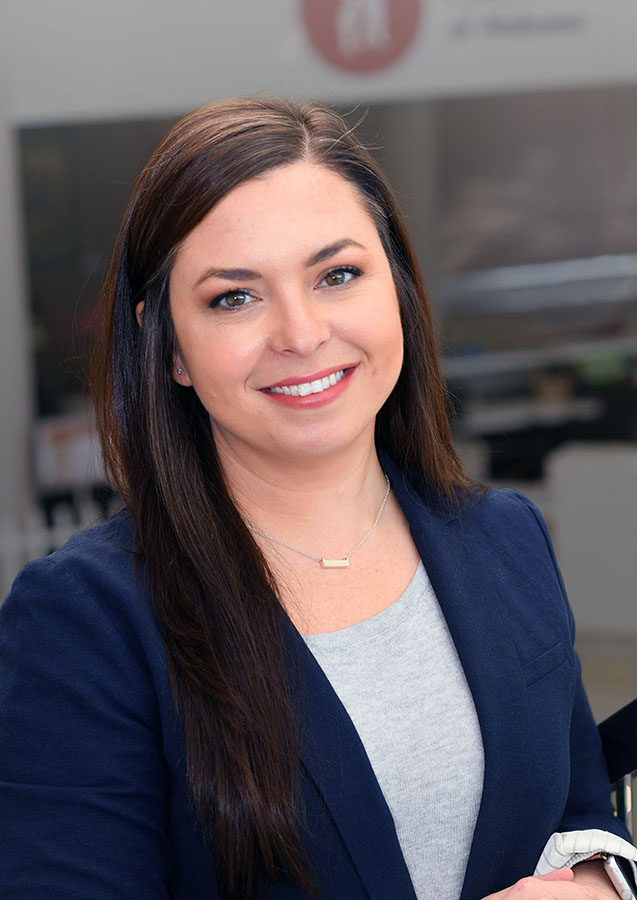 Smiling woman in blue blazer, office background.