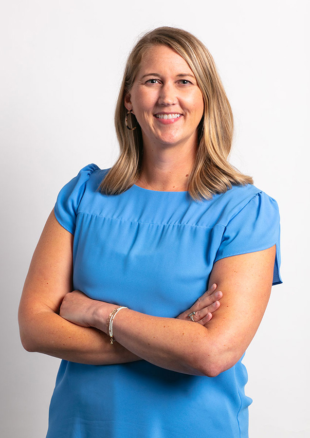 Smiling person in blue shirt with arms crossed.