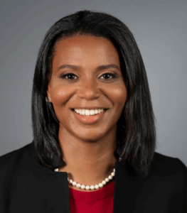 Smiling woman in professional attire and pearl necklace.